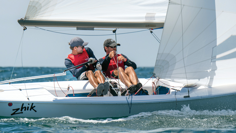 two sailors racing a dinghy sailboat. 