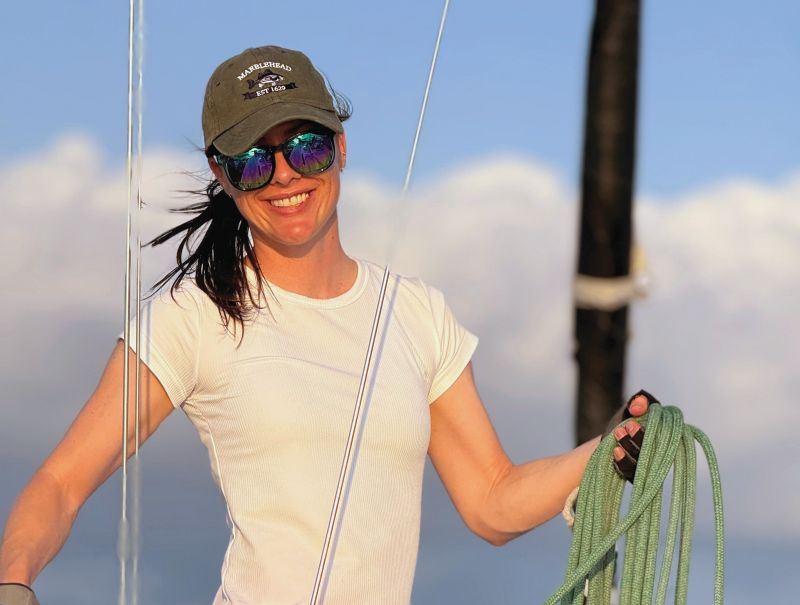 A woman on a sailboat coiling a line.