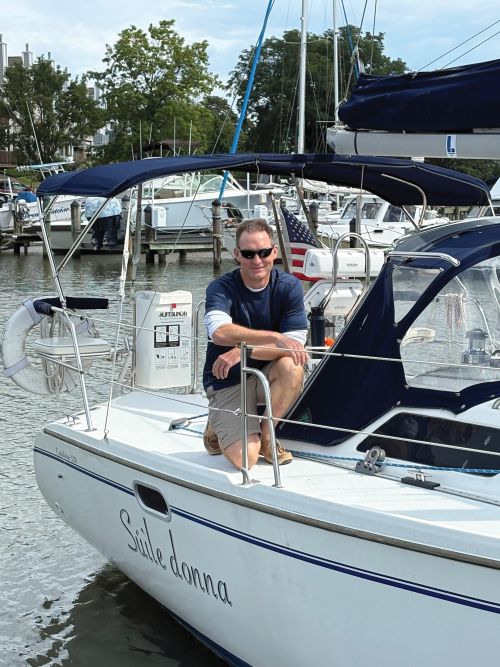 A man posing on his sailing vessel whole it's docked