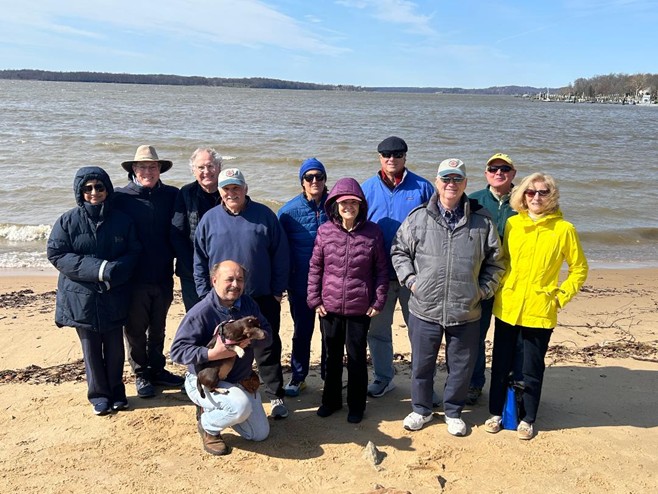 Members of the Compass Boating Club of the Chesapeake stand on the shoreline of the Chesapeake Bay