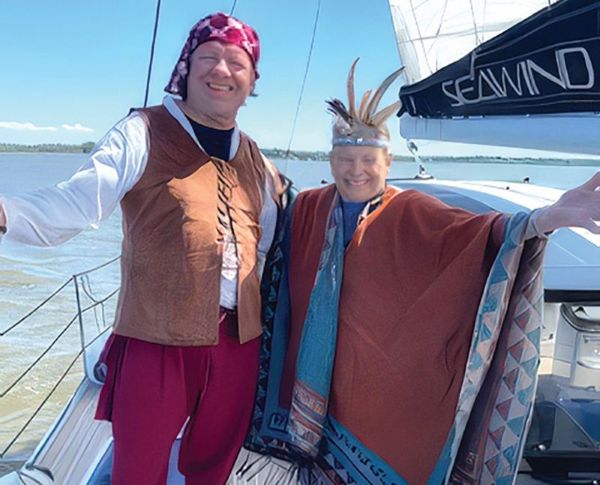 a man and a woman dressed as Capt. John Smith and Pocahontas on a sailboat