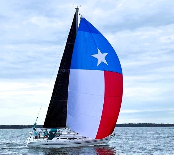 Sailboat underway, flying a red, white, and blue spinnaker