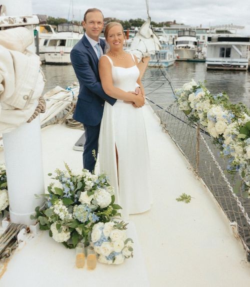 A bride and groom on a sailboat with lots of flowers adorning the boat.