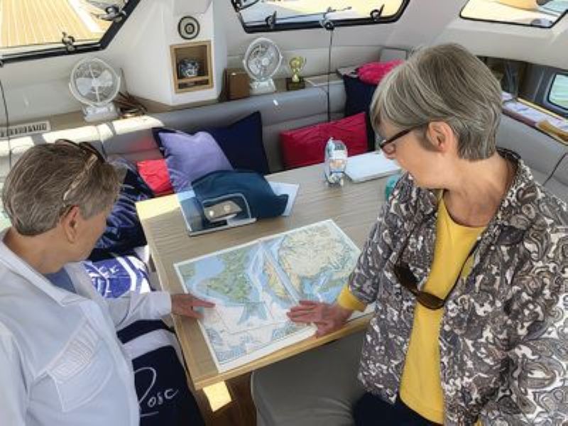 two women looking at a chart inside the saloon of a charter boat