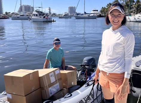 Boxes loaded in a dinghy and sailors participating in the Clean Wake program