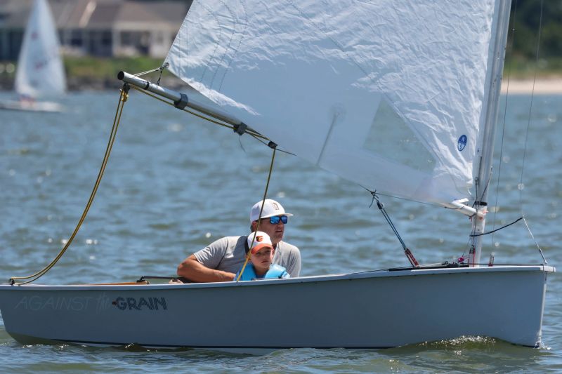 A father and son sailing a Penguin sailboat