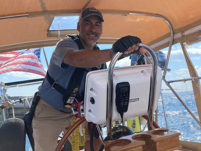 Tom at the helm while cruising in Maine cruising in Maine, man at helm of sailboat