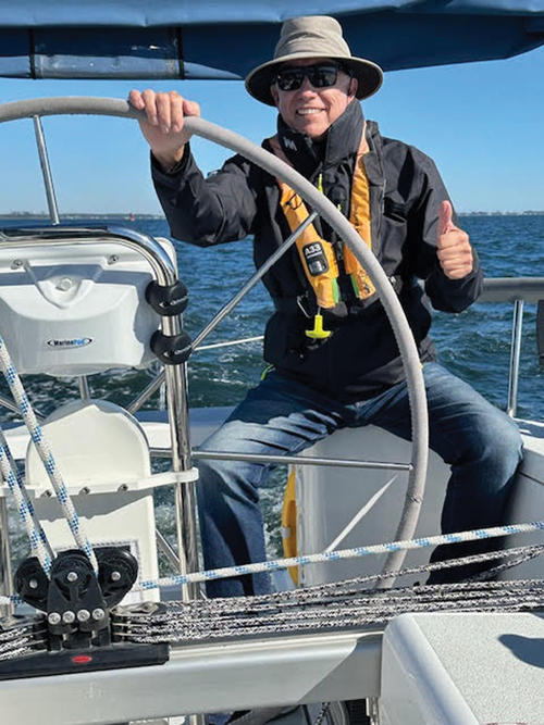 Singles on Sailboats sailor man at the wheel of a sailboat giving thumbs up